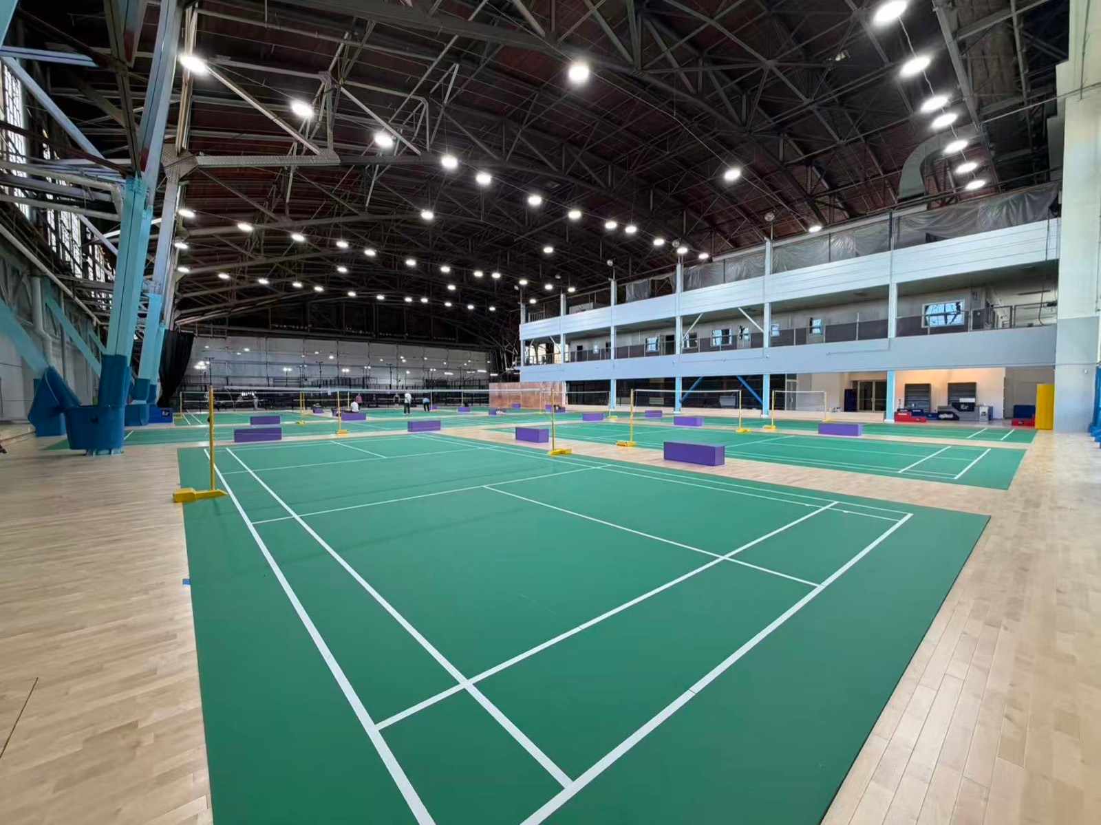Green badminton courts under the arched roof at SF Sport Club